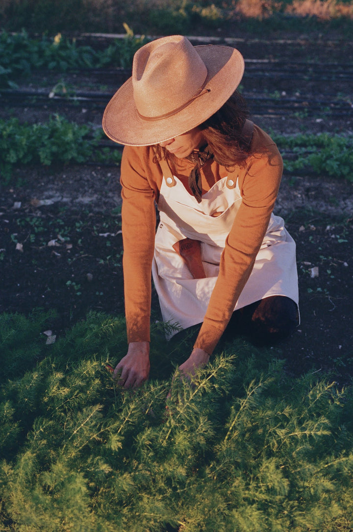 Woman gardening wearing Farm to Kitchen Savilino apron