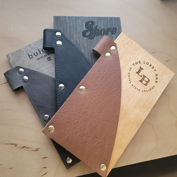 Stack of wood and leather Savilino check presenters for various restaurants