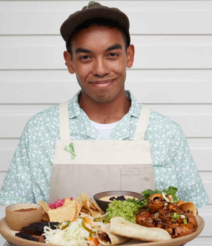 Man wearing custom Carriqui apron and shirt serving up colorful food