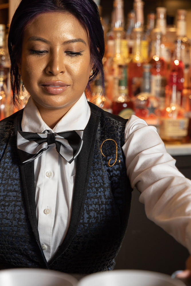 Detail of bartender wearing custom vest and uniform behind the bar