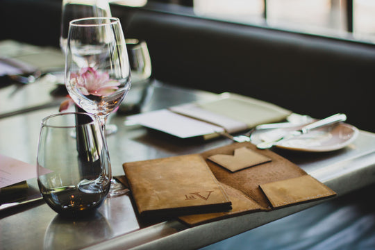 Custom Savilino check presenters and wine glasses at a restaurant table