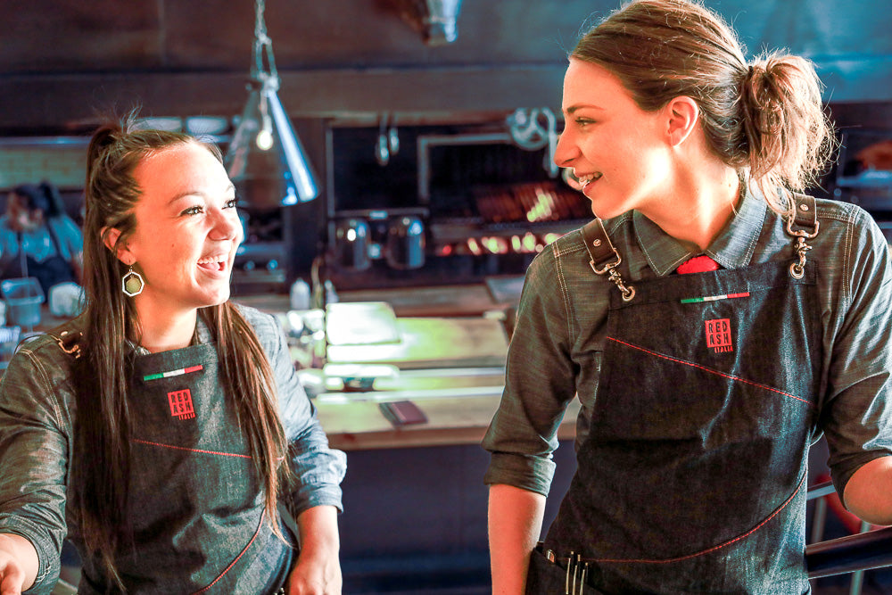 Laughing co-workers at Red Ash wearing custom Savilino bib aprons