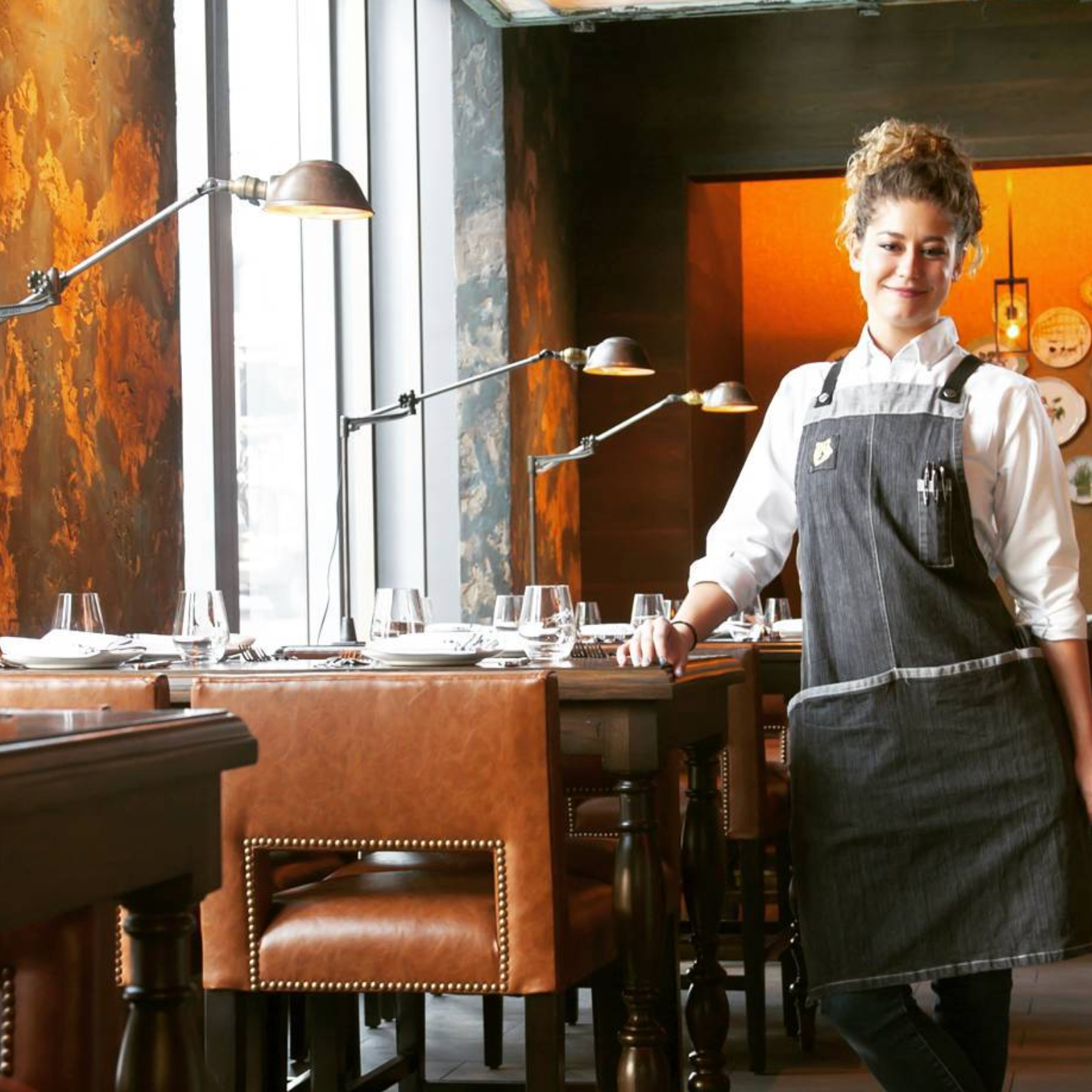 Woman smiling while wearing her Fixe bib apron custom made by Savilino